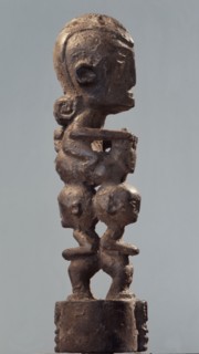 Batak figural carving depicting a figure riding an animal or serpent over the heads of two smaller figures