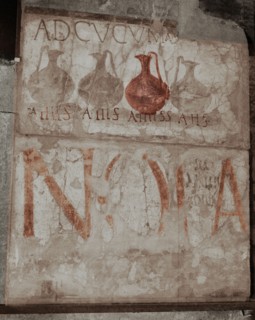 A wine shop sign in the main street, advising to come to the sign of the bowls (ad cucumas)
