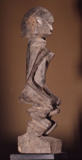 A wood sculpture of a woman, possibly an ancestor figure