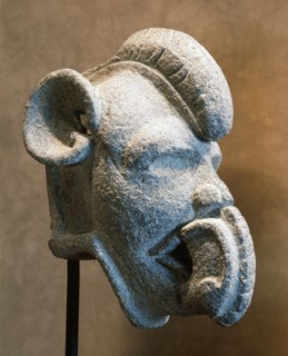 Hacha in the form of a face wearing a mouth mask