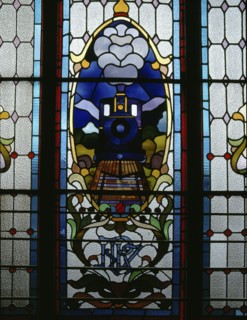 An approaching train with its headlamp alight appears in this detail of a stained glass window in Dunedin Railway Station
