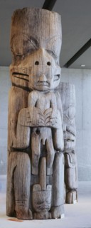 Section of a house frontal pole showing a bear holding a man