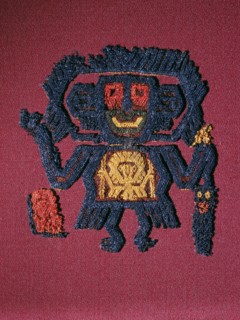 Nazca textile fragment in the form of a figure carrying a trophy head and staff