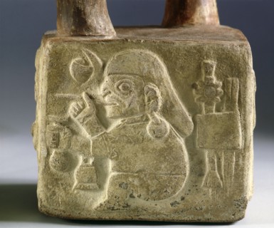 Square, stirrup spouted vessel on one side of which is carved a warrior figure