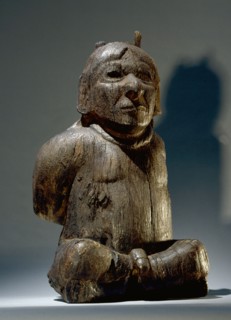 A figure of a seated prisoner with bound hands and a rope around his neck, possibly a sacrificial victim