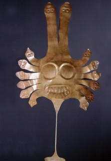 Nazca dance wand of hammered gold with a stylized feline face surrounded by machakway serpents
