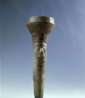 A tubular object decorated with a face and geometric patterns