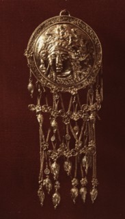 One of a pair of round forehead pendants with a relief design of Athena wearing a helmet richly ornamented with griffins from which hang elaborate crossed chains