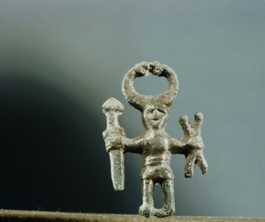 Pendant or amulet of a man holding a sword and two spears and wearing a horned helmet