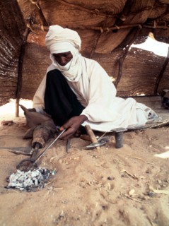 A blacksmith, possibly Tuareg or Songhay, forging iron