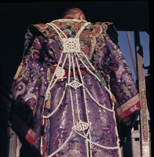 Priest dressed in brocade robes and adorned with jewellery
