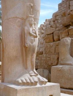 A princess, perhaps Bentanta, standing at the feet of a colossal statue of her father Ramesses II