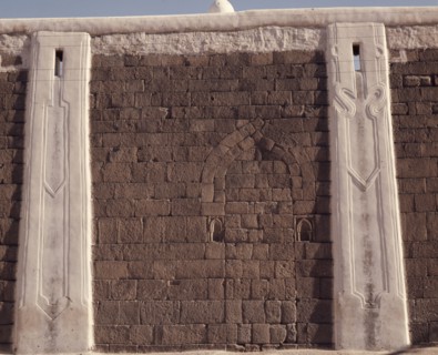 Incised plasterwork pilasters set into an old stone wall