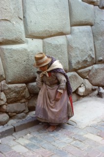 Quechua (Inca) woman in Colonial-period dress walking past typical Inca Masonry in the famous Inca Street of Hatun Rumiyoc, Cuzco