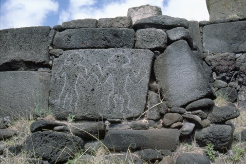 Petroglyphs of two men carved on stone slab, forming part of the foundations for the re-erected Moai platform at Anakena Bay