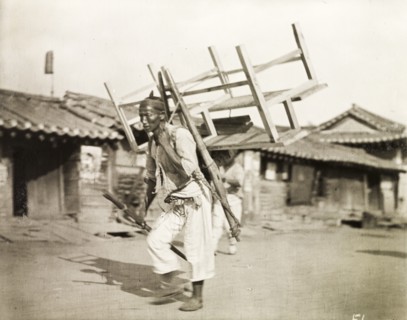 A Korean labourer carries a bench