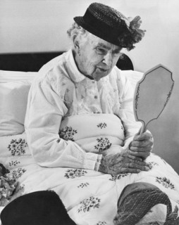 An Elderly Woman With A Mirror
