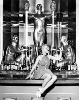 An attractive woman in a short skirt sits on a bar