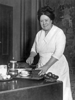 United States:  c. 1925.
A woman in a home preparing to serve coffee.