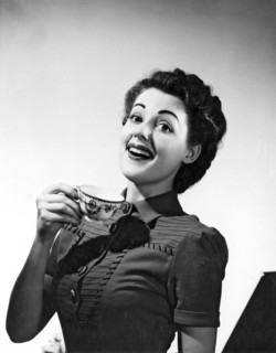 A perky woman enjoys her cup of coffee.