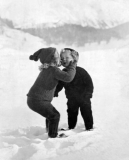 A young girl gives her little brother a kiss on the cheek in the