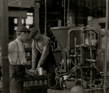 A canning machine and some of the boys] Small boys work at and around these machines some of which[?][ are dangerous.  1909