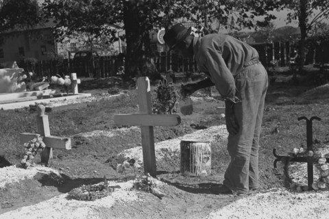 African American paints the crucifix marking a gravesite in a cemetery 1938