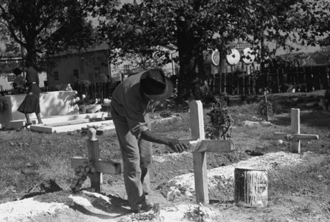 African American paints the crucifix marking a gravesite in a cemetery 1938