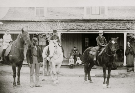 Afro-American enlisted man standing by three officers' children on horseback, Fort Verde, Arizona 1886