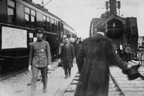 Crown Prince, in uniform walks beside a train at station