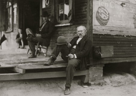 Dependent Widower sits on steps; the children work to support him 1911