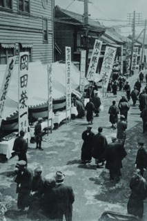 Election Day in Tokyo Japan shows a line of tables with signs in Kanji advertising political candidates