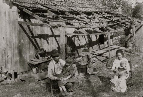 Frank Burditt and family. They rent this dilapidated shack and are trying to make a living off the meager land near by.  1921