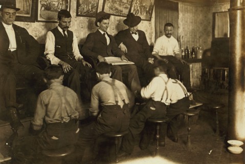 Greek Bootblacks are lined up along a shoeshine stand polishing client's shoes 1908