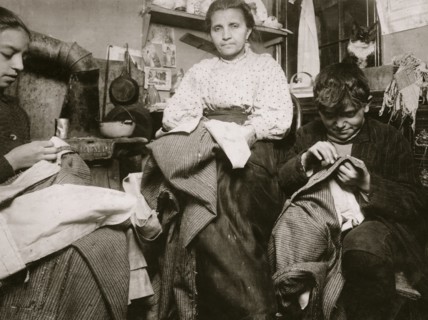 High up on the top floor of a rickety tenements, immigrants, this mother and her two children were living in a tiny one room, and were finishing garments.  1924