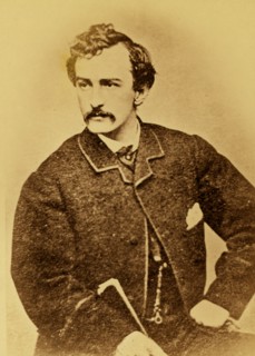 John Wilkes Booth, half-length portrait, facing left and holding a cane 1860
