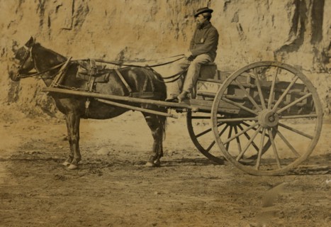 Man sitting in a horse drawn cart 1863