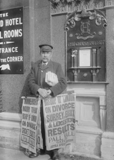 Newspaper salesman in front of Buffet Restaurant in Central London advertises News Headlines