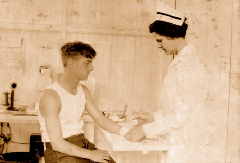 Nurse at Cheney Silk Mills bandages a boy's arm 1924
