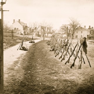 Petersburg, Va. Row of stacked Federal rifles; houses beyond 1865
