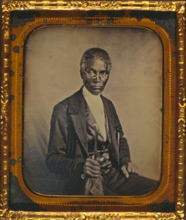 Philip Coker, three-quarter length portrait, full face, seated, wearing spectacles 1857