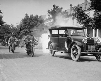 Police on motorcycles trailing car with smoke 1923