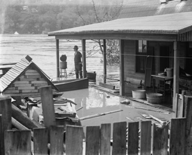 Rising River Floodwaters approach a man who stands on his front porch 1924