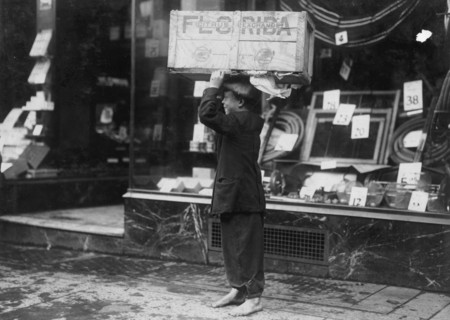 Scavenger hold a box of scavenged wood aloft. 1916