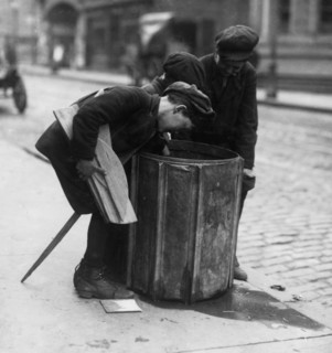 Scavengers pull fire wood from a waste basket 1916