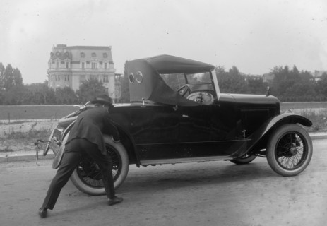 Suited man pushes his coupe from behind