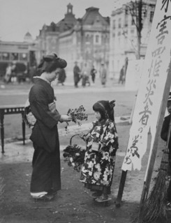 Toddler in front of Shop sign sells flowers to a kimono wearing young lady