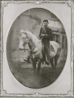 Unidentified African American soldier seated on horseback, facing left. 1865