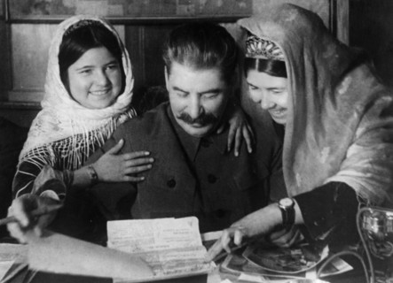 Joseph stalin with two young women from a collective farm in tadjikistan at a conference on cotton farming, january 1935.