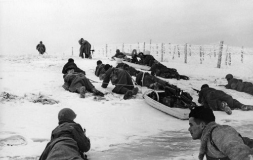 Red army troops move past frosty barbed wire dragging sleds with machine-guns on the leningrad front.